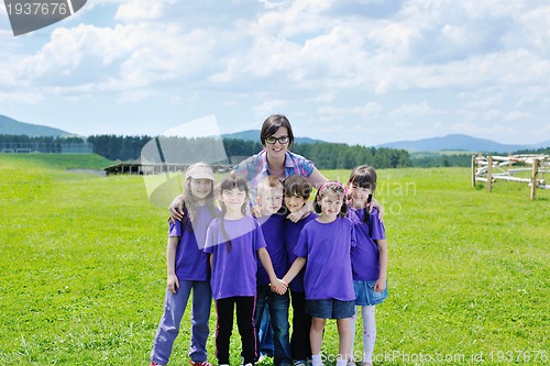 Image of happy kids group with teacher in nature