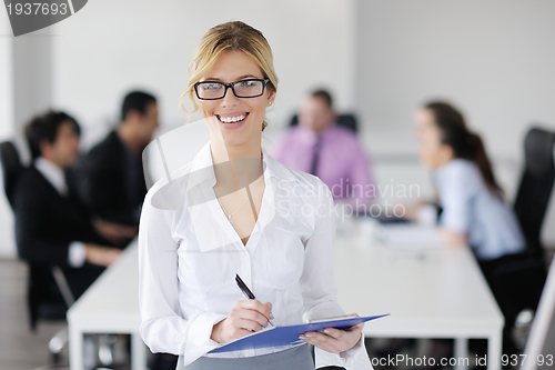 Image of business woman standing with her staff in background