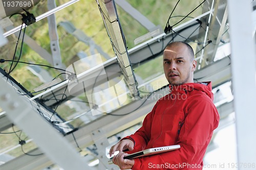 Image of engineer using laptop at solar panels plant field