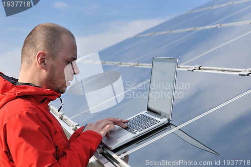 Image of engineer using laptop at solar panels plant field