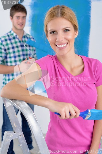 Image of happy couple paint wall at new home
