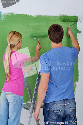 Image of happy couple paint wall at new home