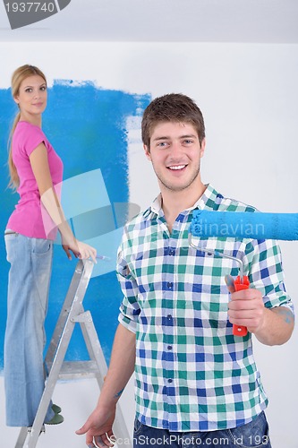 Image of happy couple paint wall at new home