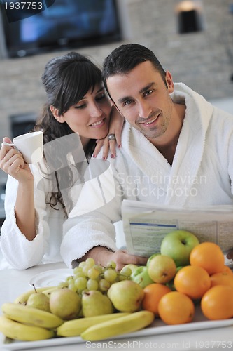 Image of Happy couple reading the newspaper in the kitchen at breakfast