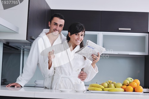 Image of Happy couple reading the newspaper in the kitchen at breakfast