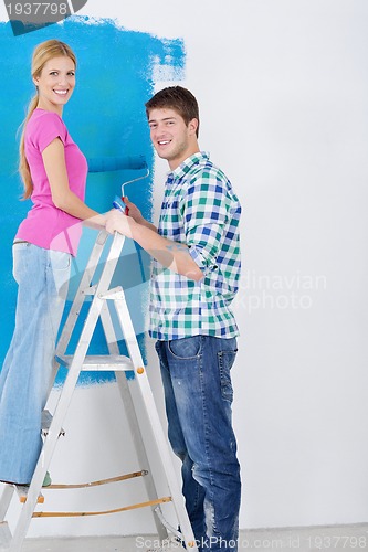 Image of happy couple paint wall at new home