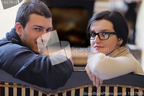 Image of Young romantic couple sitting and relaxing in front of fireplace