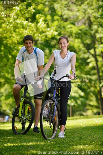 Image of Happy couple riding bicycle outdoors