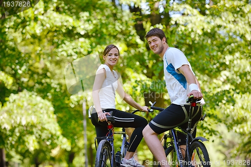 Image of Happy couple riding bicycle outdoors