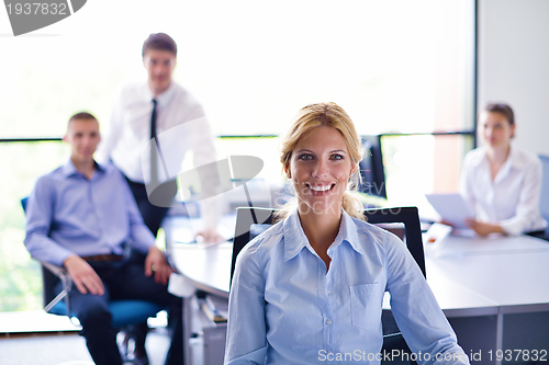 Image of business woman with her staff in background at office