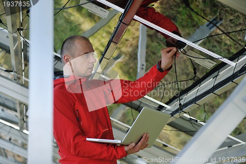 Image of engineer using laptop at solar panels plant field