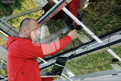 Image of engineer using laptop at solar panels plant field