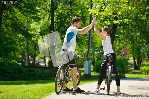 Image of Happy couple riding bicycle outdoors
