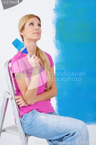 Image of happy smiling woman painting interior of house
