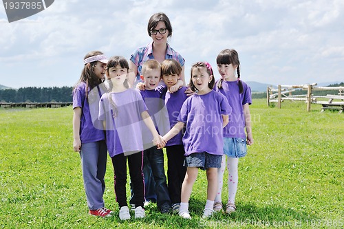 Image of happy kids group with teacher in nature