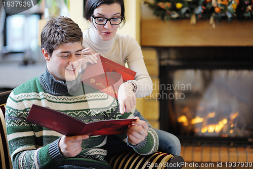 Image of Young romantic couple relax on sofa in front of fireplace at hom