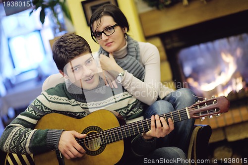 Image of Young romantic couple sitting and relaxing in front of fireplace