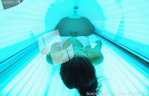 Image of Beautiful young woman tanning in solarium