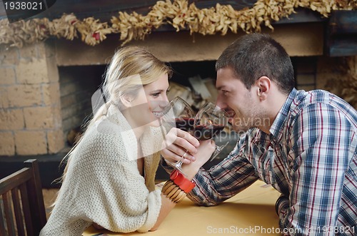 Image of Young romantic couple sitting and relaxing in front of fireplace