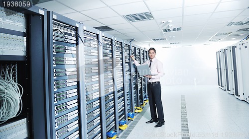 Image of businessman with laptop in network server room