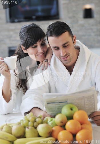 Image of Happy couple reading the newspaper in the kitchen at breakfast