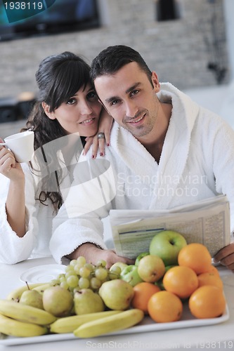Image of Happy couple reading the newspaper in the kitchen at breakfast