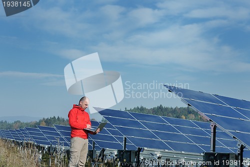 Image of engineer using laptop at solar panels plant field