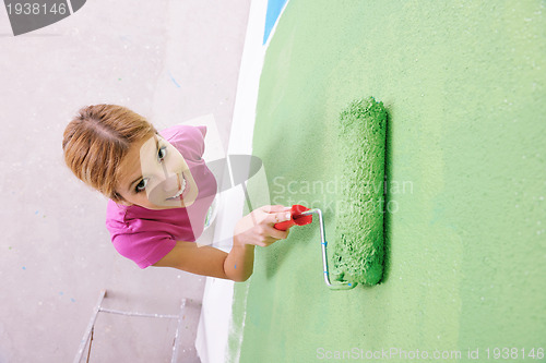 Image of happy smiling woman painting interior of house