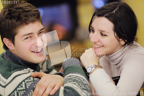 Image of Young romantic couple relax on sofa in front of fireplace at hom