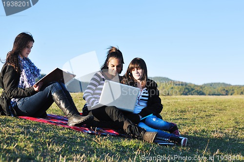 Image of group of teens working on laptop outdoor