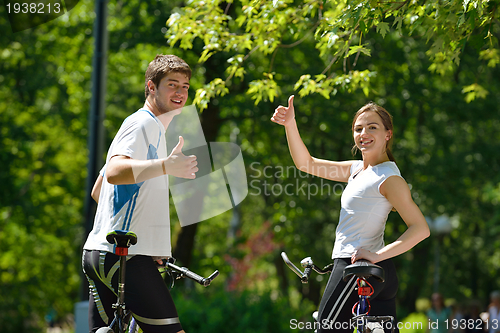 Image of Happy couple riding bicycle outdoors