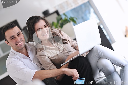 Image of joyful couple relax and work on laptop computer at modern home
