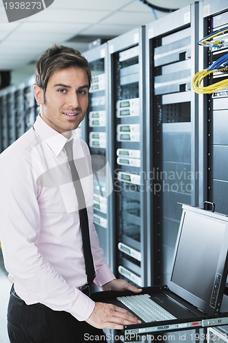 Image of businessman with laptop in network server room