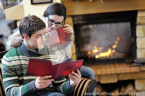 Image of Young romantic couple relax on sofa in front of fireplace at hom