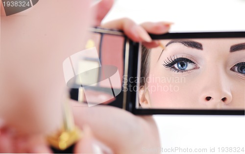 Image of beautiful young woman applying makeup