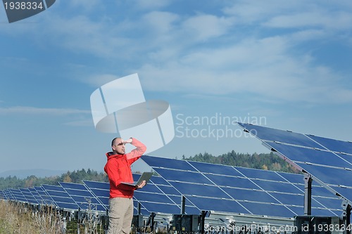 Image of engineer using laptop at solar panels plant field