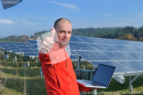 Image of engineer using laptop at solar panels plant field