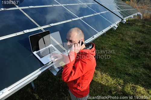 Image of engineer using laptop at solar panels plant field