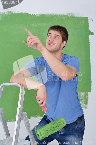 Image of handsome young man paint white wall in color