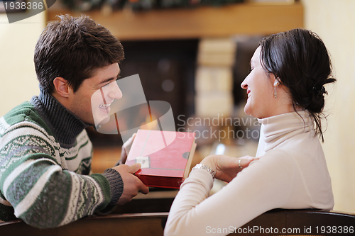 Image of Young romantic couple relax on sofa in front of fireplace at hom