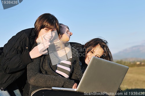 Image of group of teens working on laptop outdoor