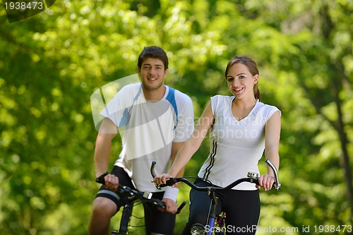 Image of Happy couple riding bicycle outdoors