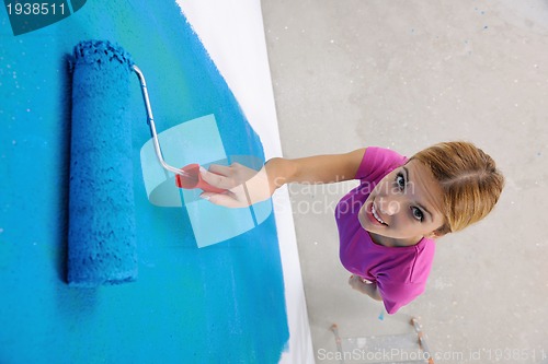Image of happy smiling woman painting interior of house