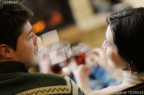 Image of Young romantic couple sitting on sofa in front of fireplace at h