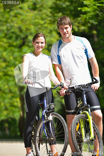 Image of Happy couple riding bicycle outdoors