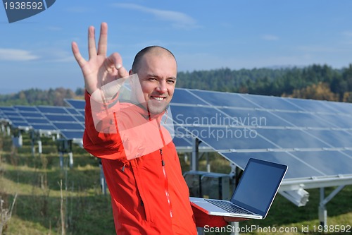 Image of engineer using laptop at solar panels plant field