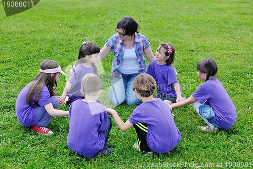 Image of happy kids group with teacher in nature