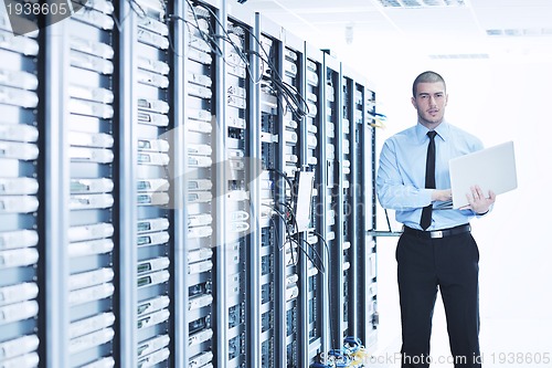 Image of businessman with laptop in network server room