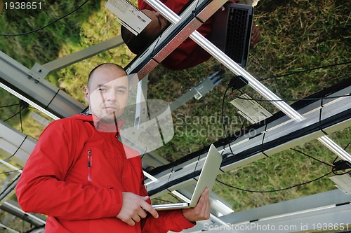 Image of engineer using laptop at solar panels plant field