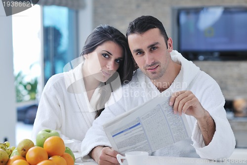 Image of Happy couple reading the newspaper in the kitchen at breakfast
